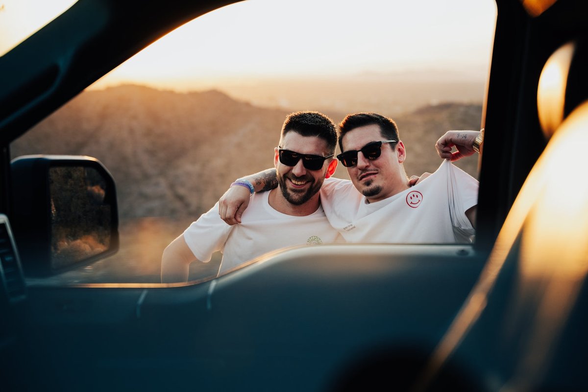 Two grinning friends in a truck at golden hour in the desert