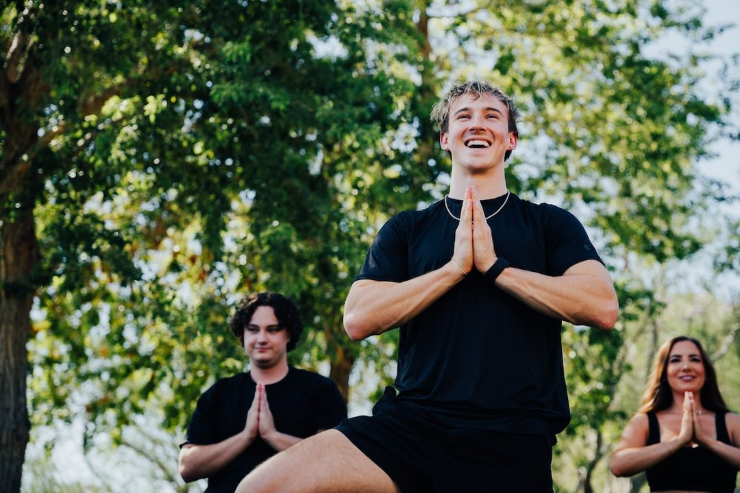 Group yoga class outdoors, leader in prayer pose